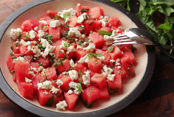 Colorful watermelon feta mint salad in a white serving bowl with fresh mint garnish on a rustic wooden table
