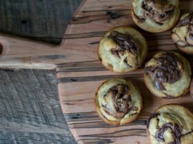 Freshly baked golden homemade cinnamon rolls with cream cheese glaze drizzled on top, arranged on a rustic wooden board with a cup of coffee nearby