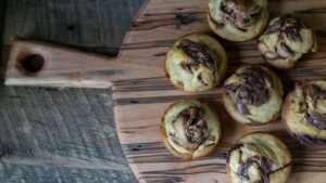 Freshly baked golden homemade cinnamon rolls with cream cheese glaze drizzled on top, arranged on a rustic wooden board with a cup of coffee nearby