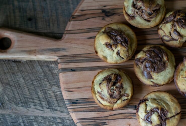 Freshly baked golden homemade cinnamon rolls with cream cheese glaze drizzled on top, arranged on a rustic wooden board with a cup of coffee nearby