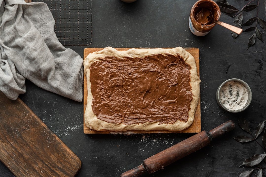 Step-by-step photo showing cinnamon roll dough being rolled out with brown sugar and cinnamon filling spread across the surface