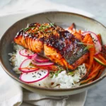 Beautifully plated miso glazed salmon with caramelized golden glaze on white plate with steamed rice and vegetables