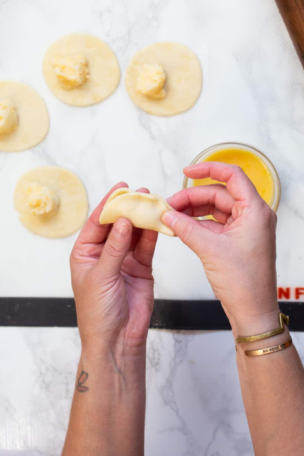 Step-by-step shots showing pierogi dough being rolled out, filled, and sealed, with hands demonstrating the proper folding technique