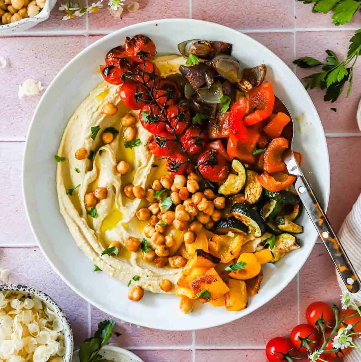 Roasted chickpea and vegetable hummus bowl beautifully plated with creamy hummus, crispy golden chickpeas, colorful fresh vegetables, and a drizzle of olive oil