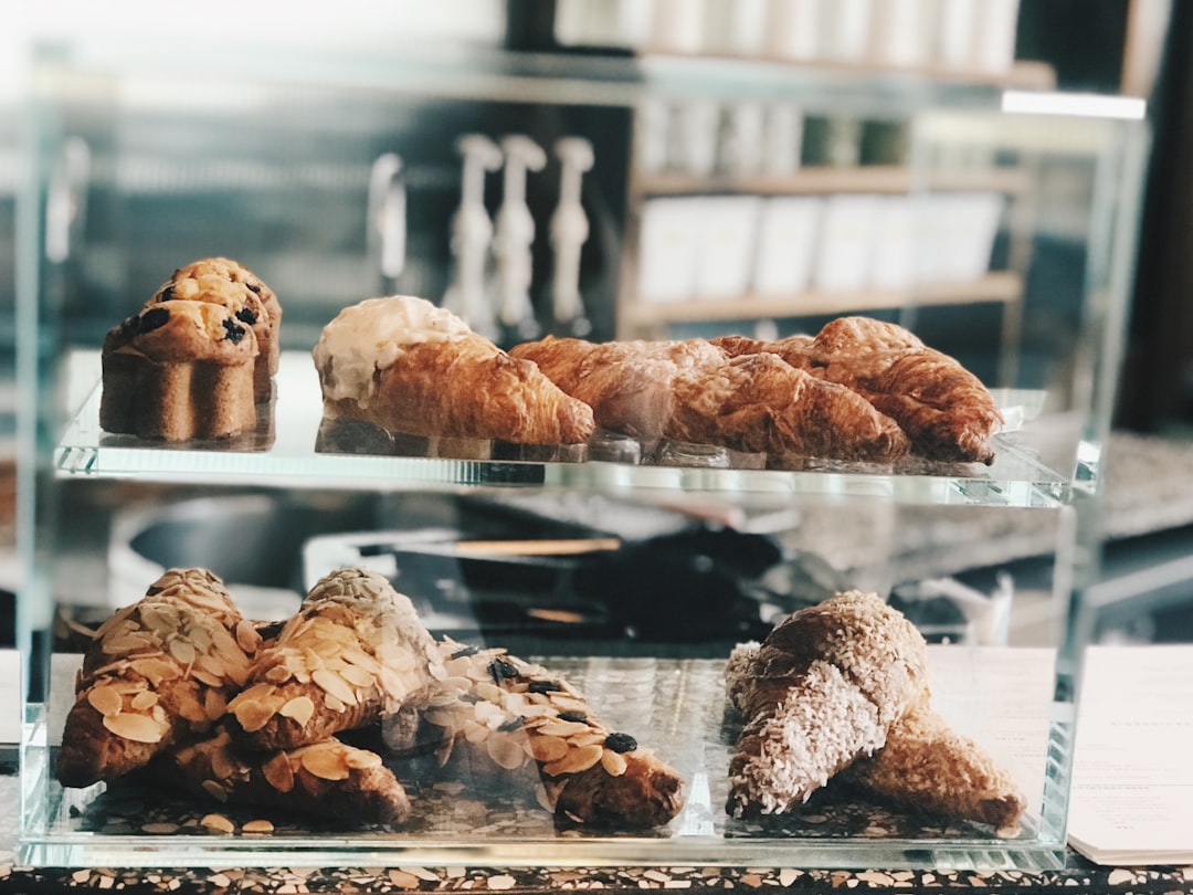 Ingredients laid out on a marble counter including bowls of ricotta cheese, powdered sugar, chocolate chips, and pistachios next to crispy cannoli shells