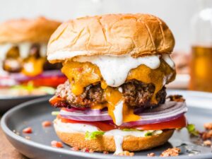 Bacon Ranch Burgers stacked high with crispy bacon, melted cheddar, and ranch drizzle on a wooden board
