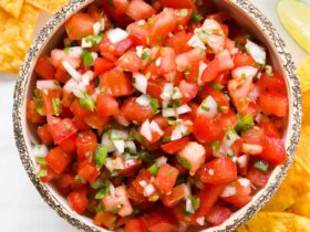Fresh Pico de Gallo in a rustic bowl with tortilla chips, diced tomatoes, cilantro, and lime wedges on a wooden board