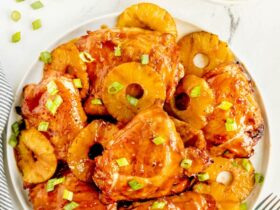 Huli Huli Chicken plated on a wooden board with caramelized pineapple glaze and fresh green onions garnish
