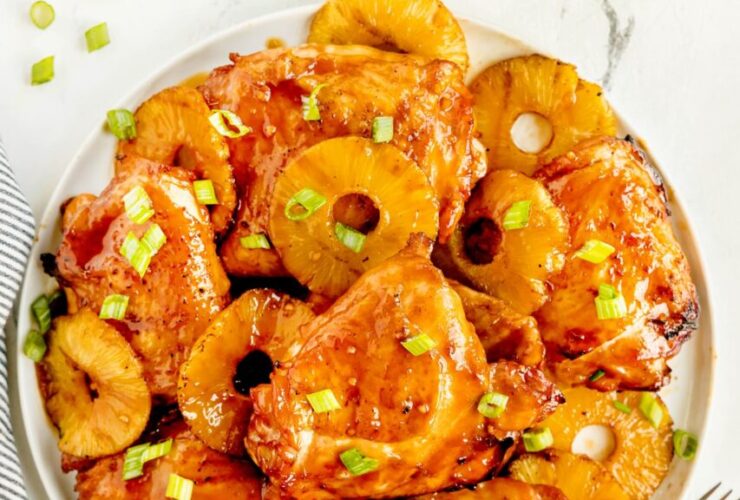 Huli Huli Chicken plated on a wooden board with caramelized pineapple glaze and fresh green onions garnish