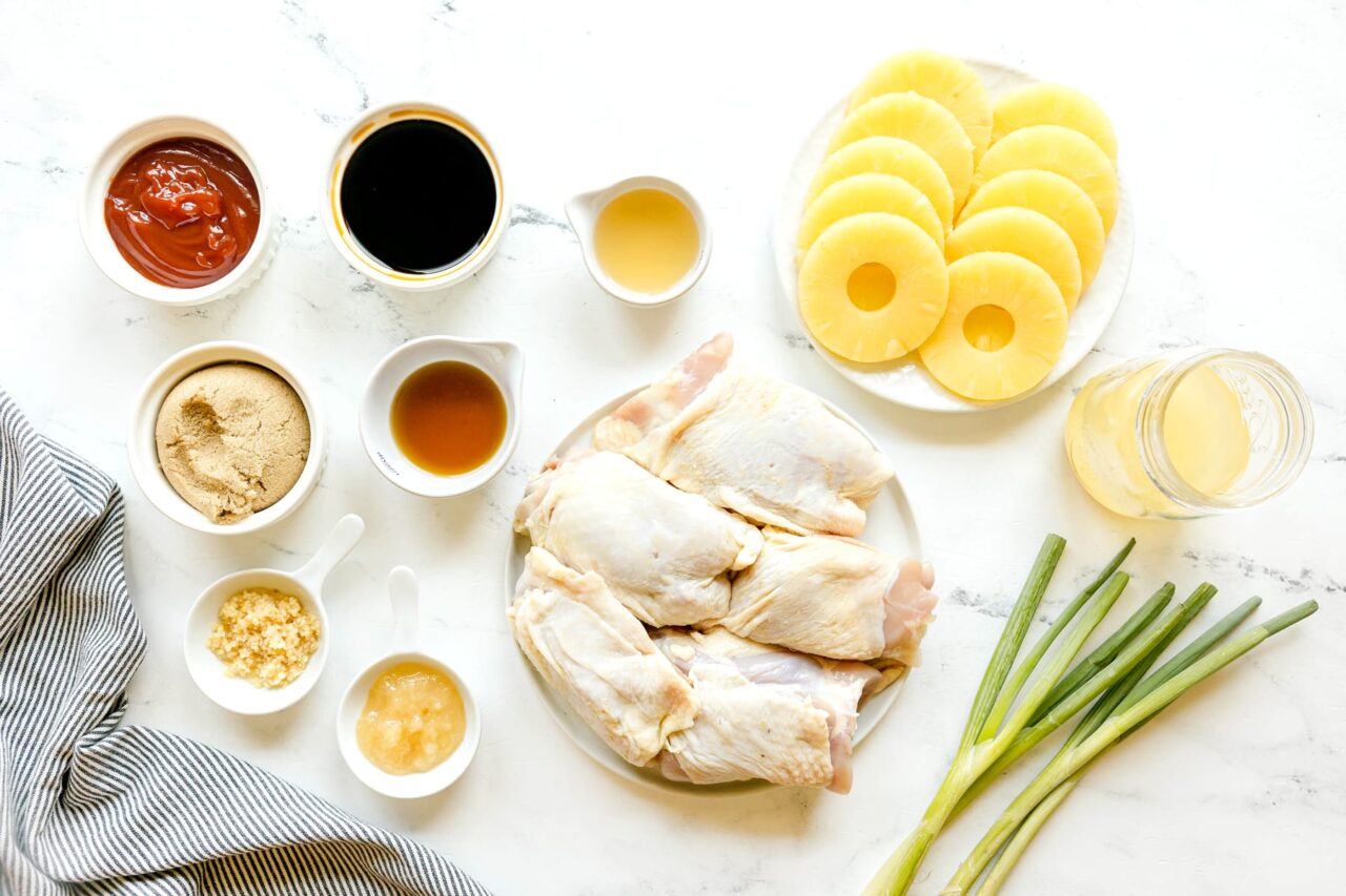 Huli Huli Chicken marinade ingredients in small bowls with raw chicken thighs on a sheet pan ready to marinate
