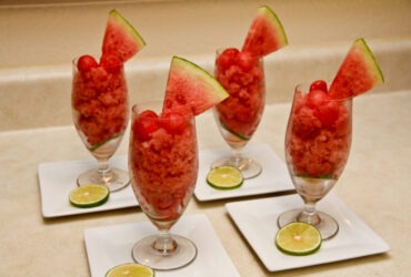 Watermelon lime granita served in a chilled glass bowl with lime wedge and fresh mint garnish on a sun-drenched outdoor table