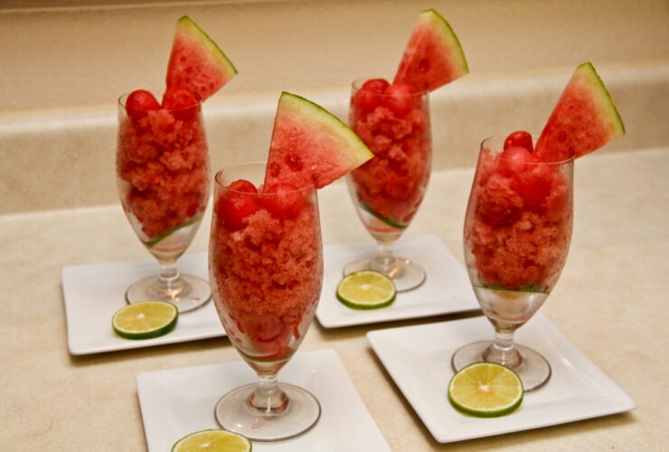 Watermelon lime granita served in a chilled glass bowl with lime wedge and fresh mint garnish on a sun-drenched outdoor table