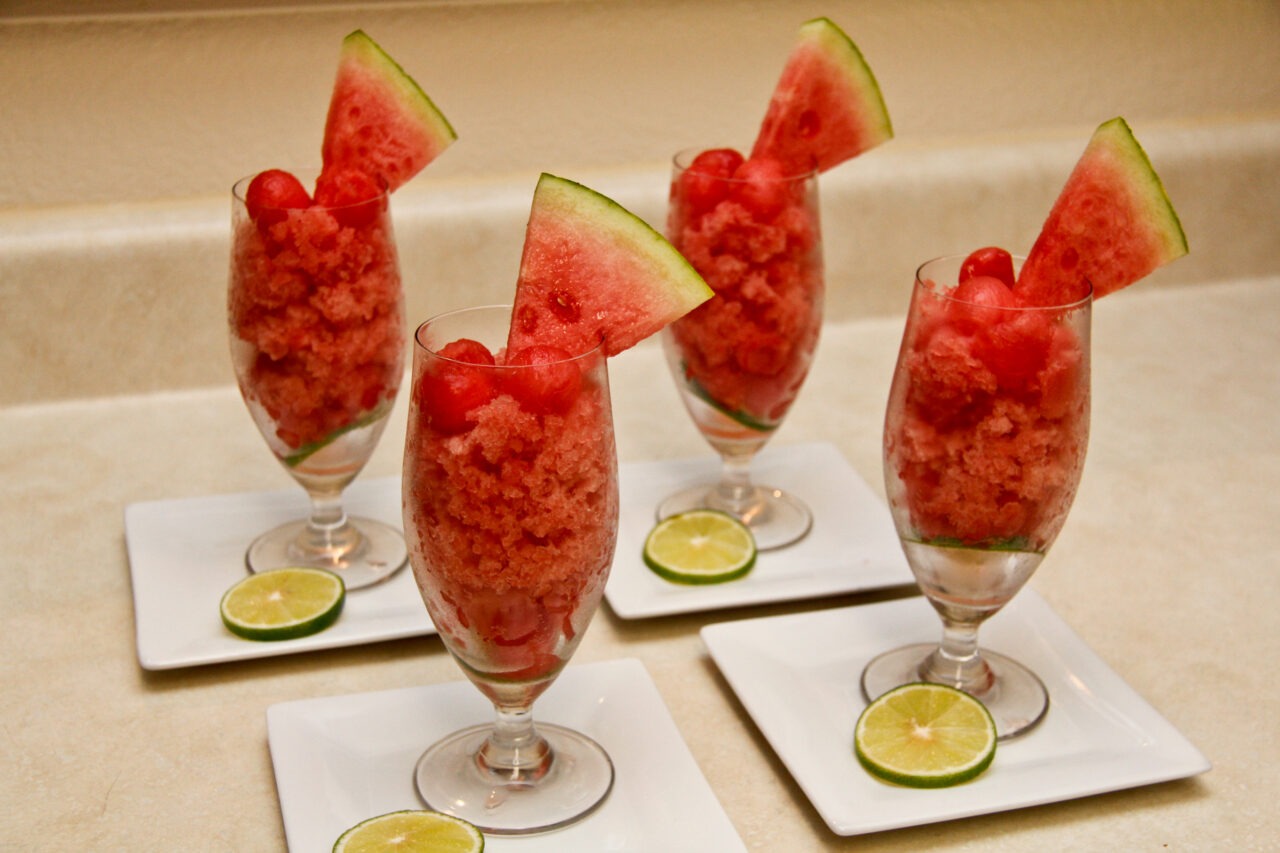 Watermelon lime granita served in a chilled glass bowl with lime wedge and fresh mint garnish on a sun-drenched outdoor table
