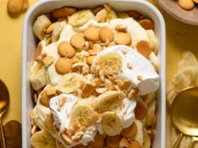 A beautiful overhead shot of classic Southern banana pudding in a large trifle dish, showing golden vanilla wafer layers, sliced bananas, and fluffy whipped topping garnished with crushed wafers