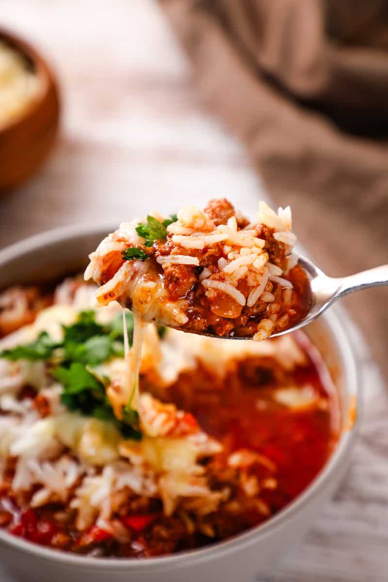 Close-up of a ladle scooping Crockpot Stuffed Pepper Soup from a slow cooker, showing the colorful bell peppers, rice, and rich tomato broth