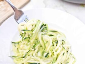 Garlic Parmesan Zoodles beautifully plated in a white pasta bowl, topped with freshly grated Parmesan, cracked black pepper, and fresh basil, shot overhead on a rustic wood surface