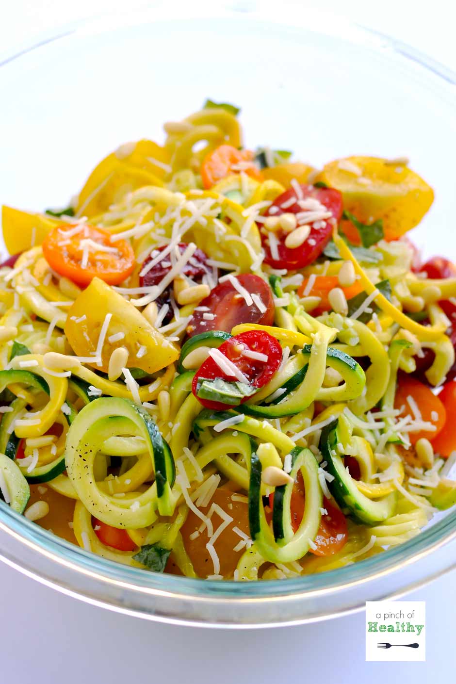 Close-up of a fork twirling Garlic Parmesan Zoodles with golden garlic bits, shaved Parmesan, and fresh basil visible, warm light and shallow depth of field