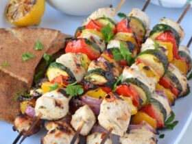 Grilled Chicken Skewers with Tzatziki served on a wooden board with warm pita, fresh cucumber slices, lemon wedges, and a generous bowl of creamy tzatziki sauce