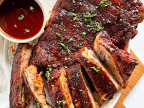 Instant Pot ribs plated on a wooden board with BBQ sauce glaze, charred edges, and fresh herbs garnish
