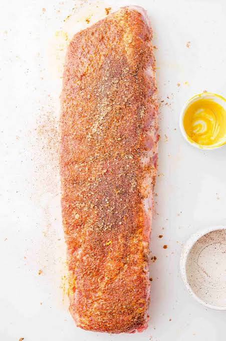 Step-by-step ingredients flat lay showing dry rub spices, baby back ribs, BBQ sauce bottle, and apple cider vinegar on a kitchen counter