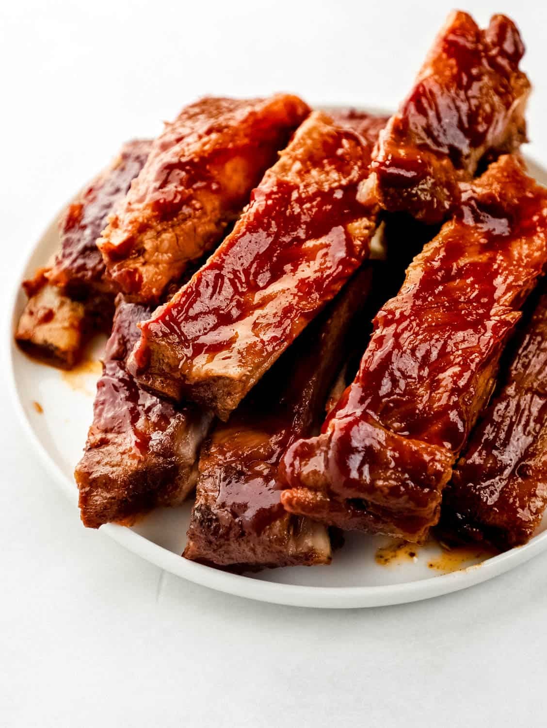 Close-up of glazed Instant Pot ribs being pulled apart to show tender, juicy meat with BBQ sauce dripping