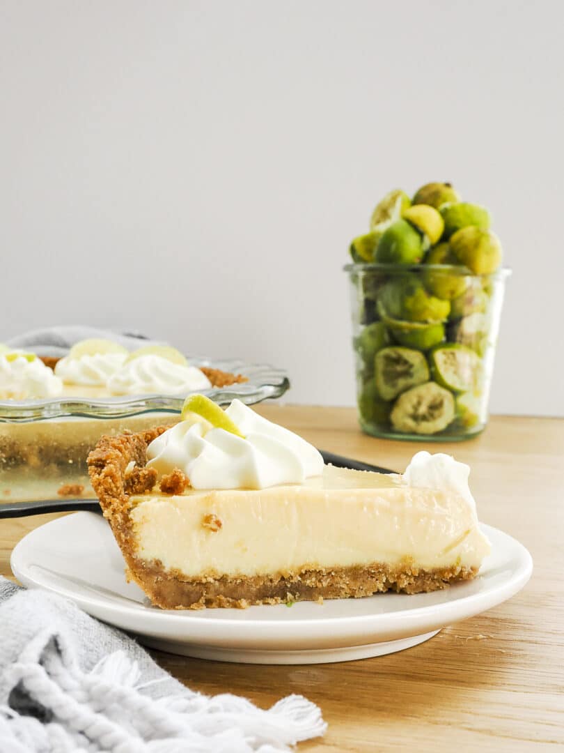 Key Lime Pie ingredients laid out on a marble surface — condensed milk, key limes, eggs, graham crackers, and butter with a mixing bowl