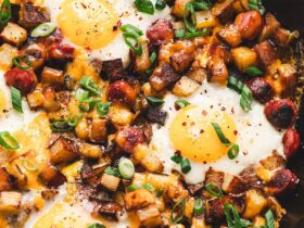 One pan camping breakfast skillet with eggs, crispy potatoes, colorful peppers and sausage in a cast iron pan, served hot and golden