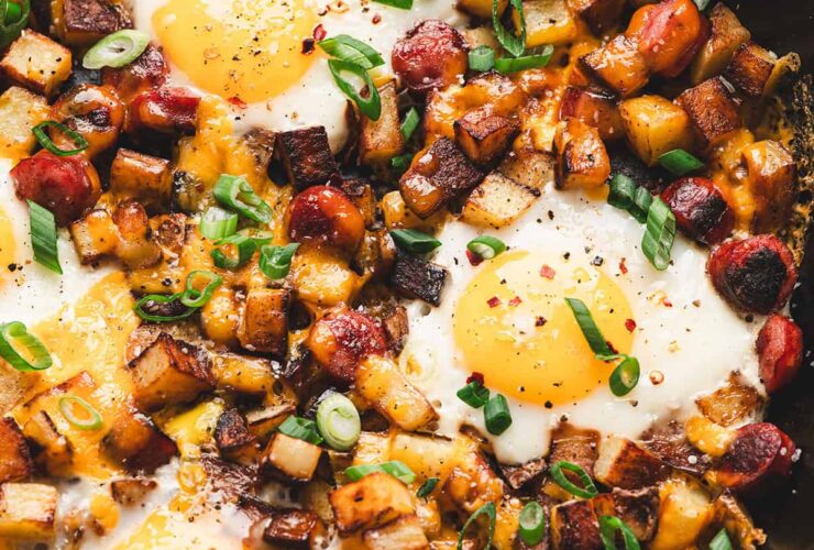 One pan camping breakfast skillet with eggs, crispy potatoes, colorful peppers and sausage in a cast iron pan, served hot and golden
