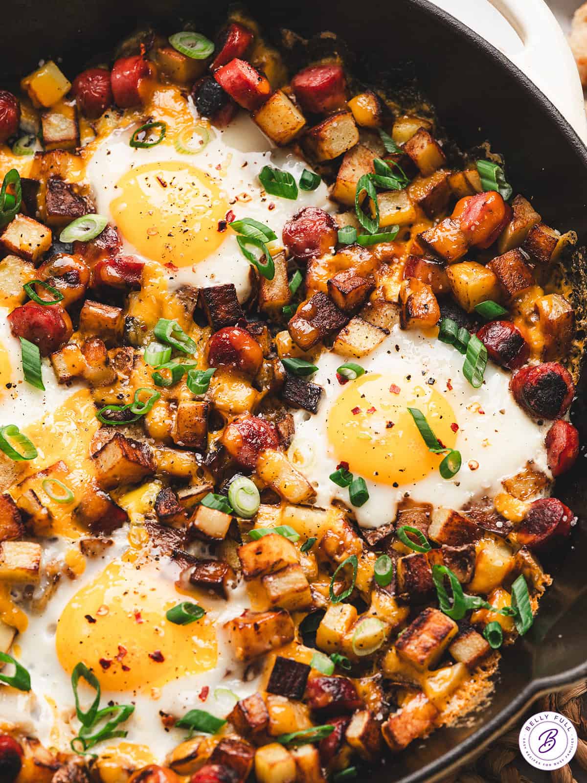 One pan camping breakfast skillet with eggs, crispy potatoes, colorful peppers and sausage in a cast iron pan, served hot and golden