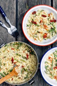 One pot cheesy orzo with asparagus served in a wide shallow bowl, topped with shaved Parmesan and fresh lemon zest, garnished with cracked black pepper, soft natural light