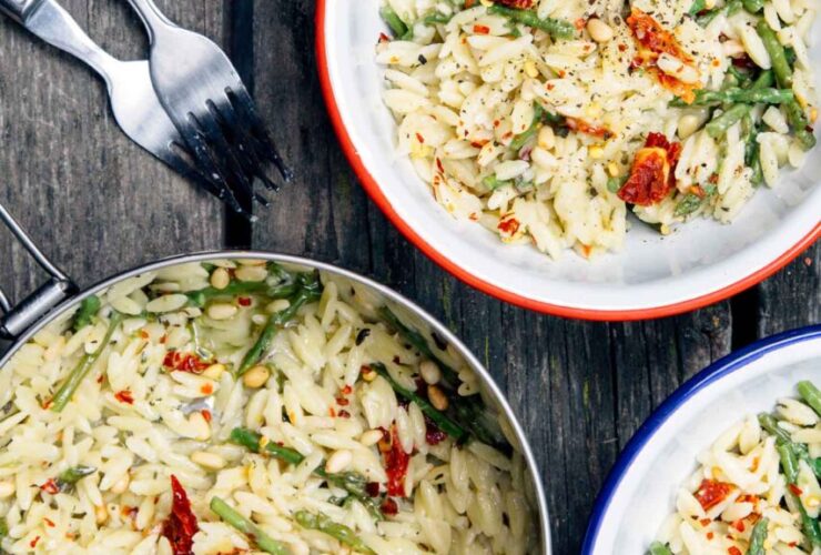 One pot cheesy orzo with asparagus served in a wide shallow bowl, topped with shaved Parmesan and fresh lemon zest, garnished with cracked black pepper, soft natural light