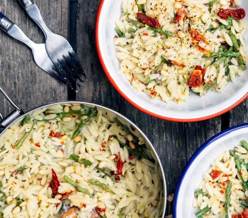 One pot cheesy orzo with asparagus served in a wide shallow bowl, topped with shaved Parmesan and fresh lemon zest, garnished with cracked black pepper, soft natural light
