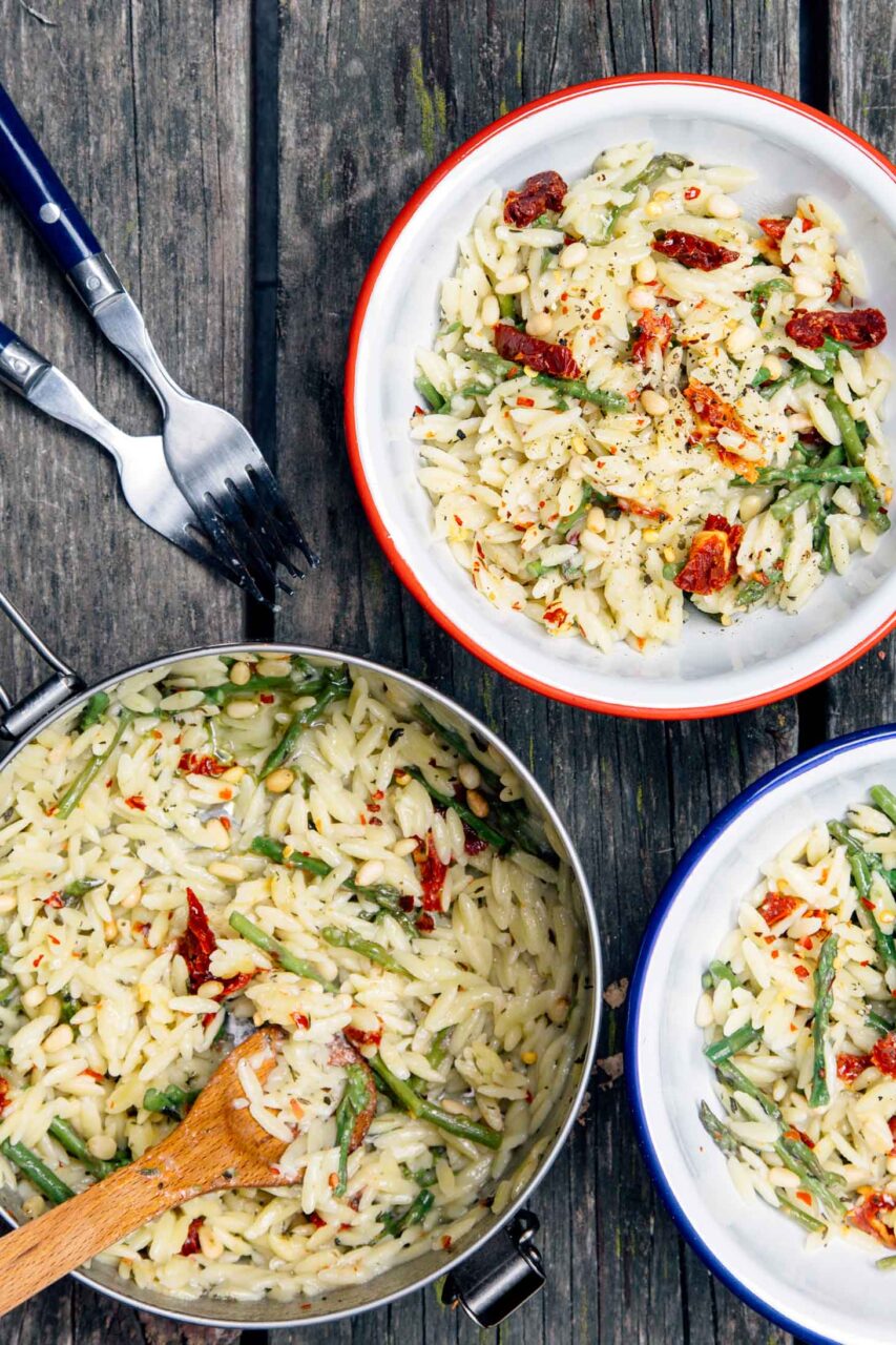 One pot cheesy orzo with asparagus served in a wide shallow bowl, topped with shaved Parmesan and fresh lemon zest, garnished with cracked black pepper, soft natural light