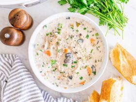 Slow cooker chicken wild rice soup served in a rustic white bowl, garnished with fresh thyme and cracked black pepper, with a spoon resting on the side