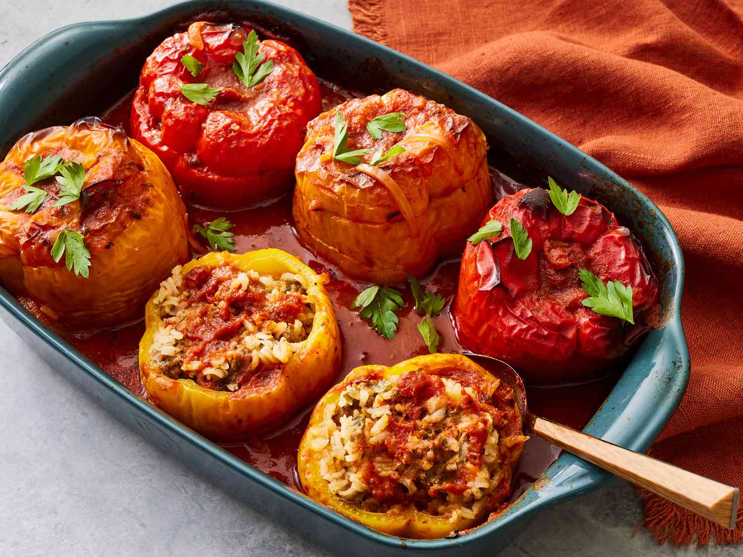 Ground beef, cooked white rice, diced tomatoes, shredded cheese, garlic, and halved bell peppers arranged on a white marble countertop for stuffed bell peppers ingredients shot
