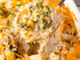 Chicken Broccoli Rice Casserole in a white baking dish with golden melted cheese on top, garnished with fresh parsley on a wooden dinner table