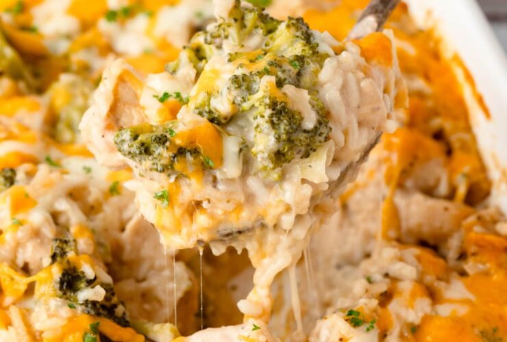 Chicken Broccoli Rice Casserole in a white baking dish with golden melted cheese on top, garnished with fresh parsley on a wooden dinner table