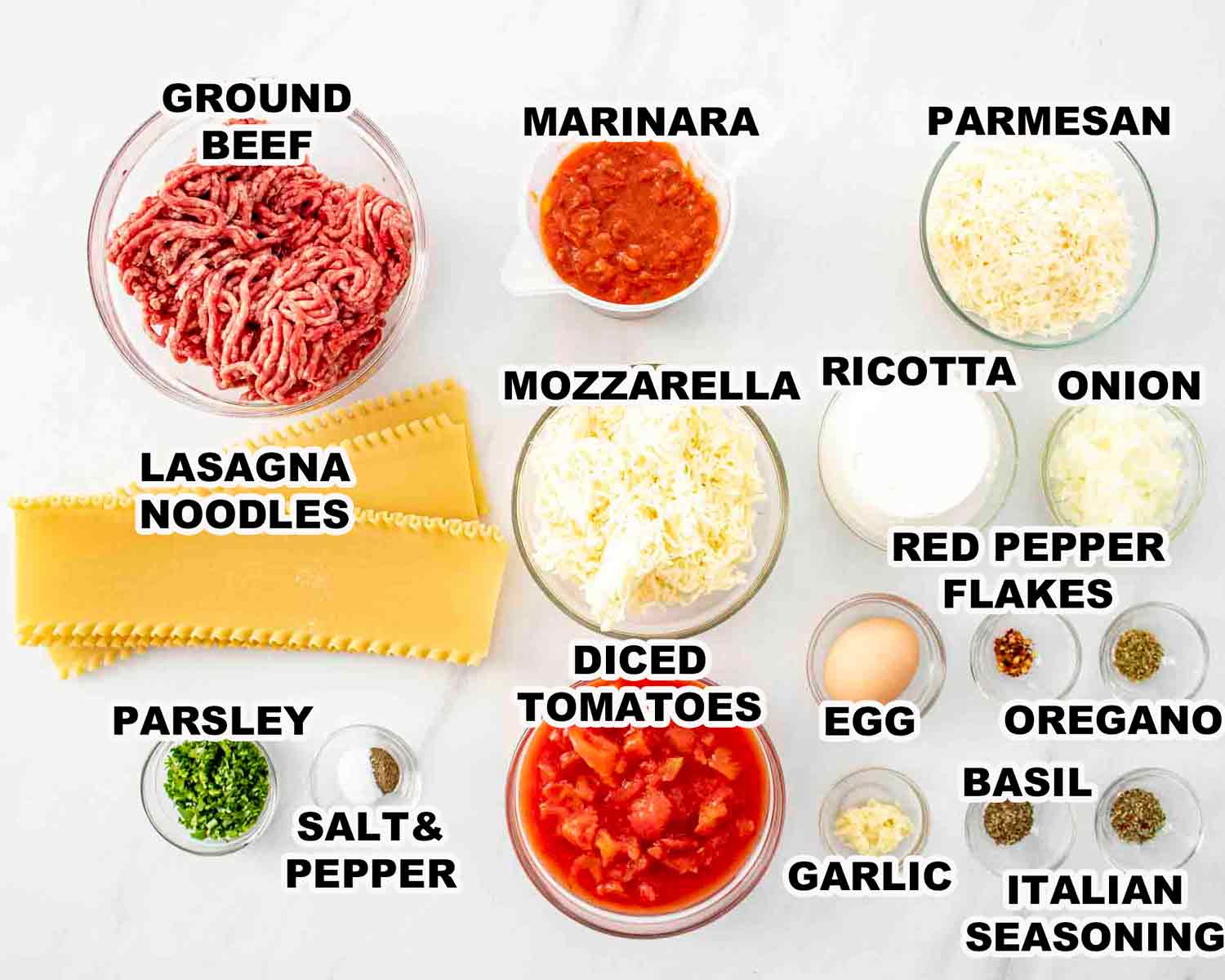 Overhead shot of slow cooker lasagna ingredients laid out on a wooden surface — ground beef, ricotta, marinara jar, mozzarella, no-boil noodles, eggs, and fresh herbs