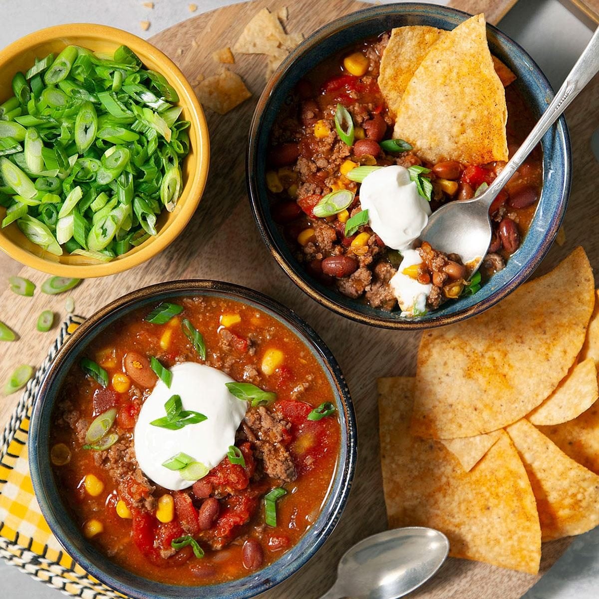 Overhead flat-lay of all the taco soup ingredients laid out on a white surface — ground beef, canned beans, corn, diced tomatoes, taco seasoning packet, shredded cheese, and broth carton