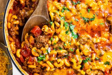 American goulash in a large pot, garnished with fresh parsley, showing tender macaroni and ground beef in a rich tomato sauce