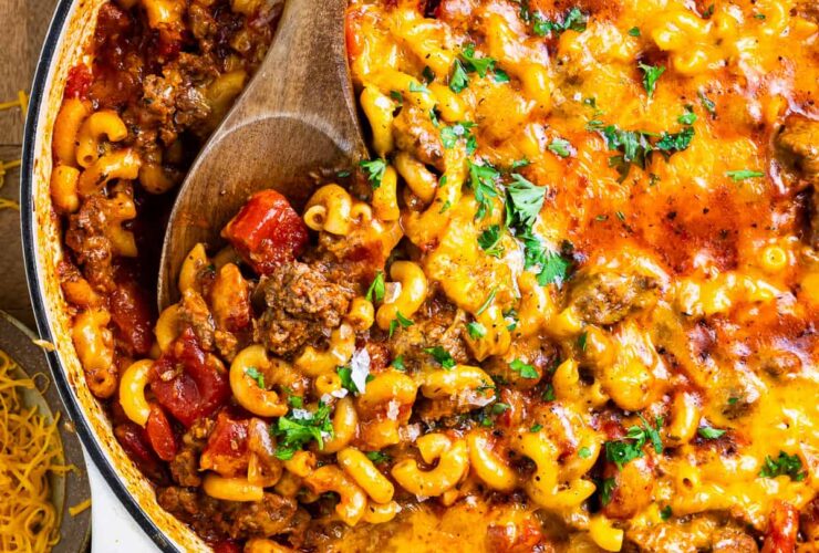American goulash in a large pot, garnished with fresh parsley, showing tender macaroni and ground beef in a rich tomato sauce