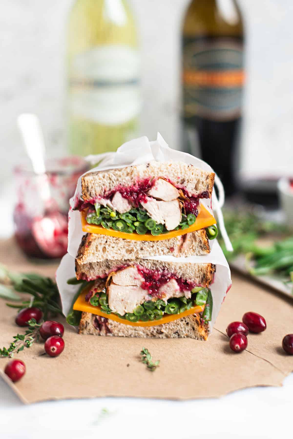 Close-up of leftover turkey sandwich cut in half, showing layers of pulled turkey, melted provolone, crispy stuffing, and cranberry aioli on golden toasted sourdough