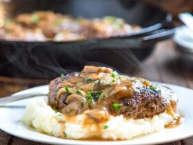 Salisbury steak beef patties smothered in rich onion mushroom gravy served over creamy mashed potatoes on a white dinner plate