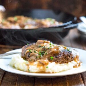 Salisbury steak beef patties smothered in rich onion mushroom gravy served over creamy mashed potatoes on a white dinner plate